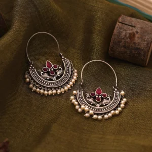 Saara red stone oxidised hoop earrings with peacock motifs and faux pearl drops on olive fabric